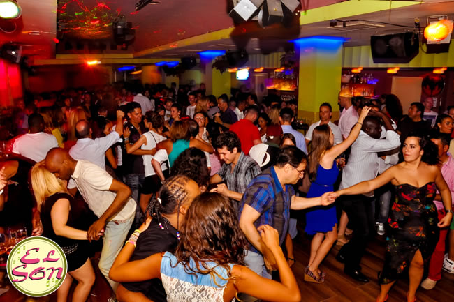 personas socializando y bailando salsa en discoteca el son